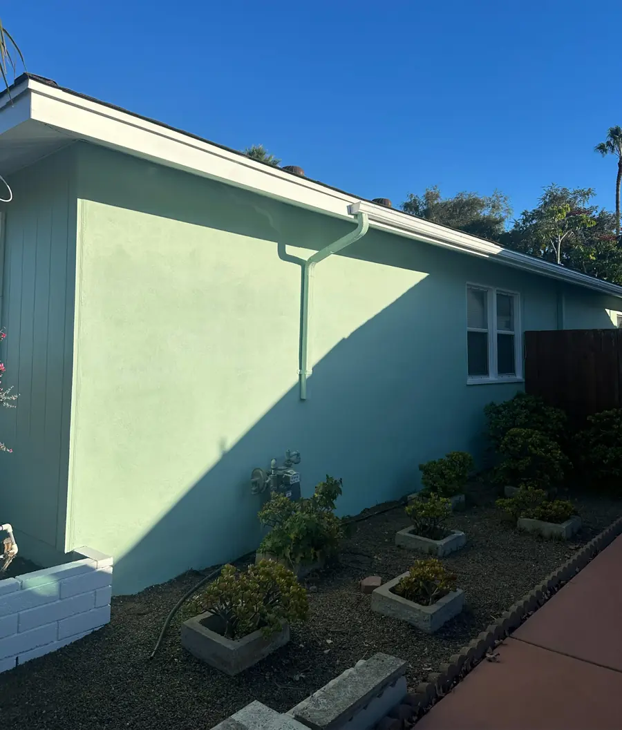 After: side of home evenly finished in seafoam exterior coating with matching downspout