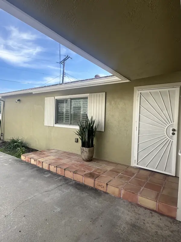 Front entry with a sage exterior coating, white security door, and terracotta tile step